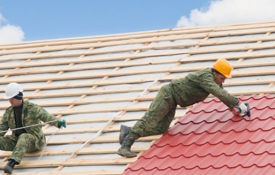 two workers on roof at works with metal tile and roofing iron